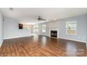 Open living room features beautiful hardwood floors, a ceiling fan, and a cozy fireplace at 12829 Brandenburg Ln, Midland, NC 28107