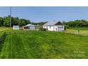 Scenic property showcasing a well-maintained home with a metal roof, detached garage, and expansive green space at 1640 Bear Poplar Rd, Cleveland, NC 27013