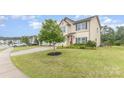 Well-manicured lawn with a young tree in the yard of a charming two-story home at 3304 Saddlebrook Dr, Midland, NC 28107