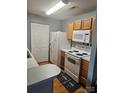 Functional kitchen equipped with white appliances and wood cabinetry, ready for your culinary creations at 3944 Town Center Rd, Harrisburg, NC 28075