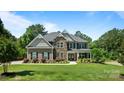 Charming two-story home with a stone and brown exterior, complemented by a lush green lawn and mature trees at 3963 Harmattan Dr, Denver, NC 28037