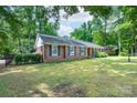 A traditional brick home featuring dark shutters, lush greenery, and a fenced yard, creating a private outdoor space at 5720 Amity Pl, Charlotte, NC 28212