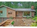 Exterior view of a home featuring a stone pathway, brick accents, and lush landscaping with large trees at 617 Pinecrest St, Davidson, NC 28036