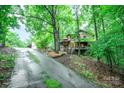 View of a two-story home with mature landscaping and wooden exterior, up a sloping driveway at 676 Cottingham Ne Pl, Concord, NC 28025