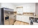 Well-lit kitchen featuring stainless steel appliances, white cabinets, tiled backsplash, and durable laminate flooring at 899 Wendover Rd # 29, Statesville, NC 28677