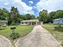 Cozy single-story home featuring a long driveway and a well-manicured front lawn with mature trees at 12423 Softwood Ct, Charlotte, NC 28273
