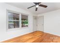 Sunlit living room with shiny hardwood floors, neutral walls, and a window overlooking green scenery at 140 Fairway Ln, Gastonia, NC 28216