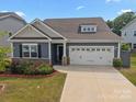Charming home featuring a two-car garage, stone accents, manicured lawn, and delightful red roses at 4427 Poplin Grove Dr, Indian Trail, NC 28079