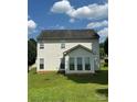 Spacious backyard with green grass, backing of the house, and a sunroom with large windows at 8125 Weeping Fig Ln, Charlotte, NC 28215
