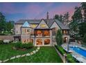 Sprawling home showcasing a balcony, covered outdoor seating, and a well-manicured lawn leading to a private pool area at 8500 Longview Club Dr, Waxhaw, NC 28173
