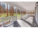 The long, covered front porch offers ample space for seating and relaxation, shaded by a white railing and pillars at 107 Rutledge Rd, Mount Holly, NC 28120