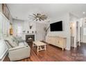 Cozy living room featuring a fireplace, ceiling fan, hardwood floors, and a comfortable couch at 108 Shade Tree Cir, Fort Mill, SC 29715