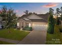 Scenic dusk view of a single-Gathering home featuring a stone facade, manicured lawn, and two-car garage at 112 E Neel Ranch Rd, Mooresville, NC 28115