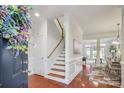Bright foyer featuring hardwood floors, staircase with white trim, and an open floor plan at 11234 Villa Trace Pl, Charlotte, NC 28277