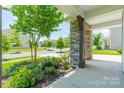 Inviting porch with stone columns, manicured shrubs and a view of the quiet, tree-lined street at 14505 Rhodes Hall Dr, Charlotte, NC 28273