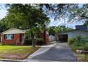View of a charming red brick home with an adjacent detached garage and storage shed at 208 S Thompson St, Monroe, NC 28112