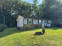 Quaint single-story home featuring light siding, black shutters, and lush green lawn with mature trees at 212 E Texas Ave, Bessemer City, NC 28016