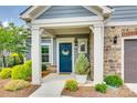 Inviting front porch featuring a blue door with wreath and meticulously maintained landscaping at 2261 Lincolnshire Ln, Waxhaw, NC 28173