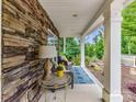 Inviting front porch with stone accent wall, cushioned seating, and a vibrant outdoor rug at 3609 Benseval Ln, Matthews, NC 28105