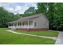 Landscaped house with a covered porch, white railings, green lawn, and long concrete driveway at 441 Vermilion Dr, York, SC 29745