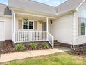 Inviting front porch with white railing, hanging plants, and seating creates a welcoming entrance to the home at 7006 Lone Eagle Dr # 18, Monroe, NC 28110