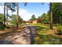 Long driveway leading to a charming brick home, surrounded by lush trees and landscaping for added privacy at 885 Roy Cline Rd, Rockwell, NC 28138