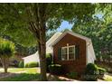 Brick and siding details on the house with lush greenery and a mature tree in the front yard at 110 Whitehall Dr, Mooresville, NC 28117