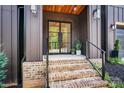 Inviting front entrance showcasing a wood trimmed porch and glass front door with brick stairs at 130 Broken Arrow Dr, Statesville, NC 28677