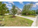 Inviting two-story home with a well-maintained lawn, mature trees, and a paved driveway leading to an attached garage at 13622 Stringfellow Ln, Charlotte, NC 28278