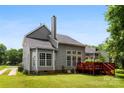 A well-maintained backyard featuring lush green grass, mature trees, and a wooden deck with stairs at 13832 Queenswater Ln, Charlotte, NC 28273