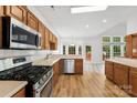 A kitchen featuring wooden cabinets, stainless steel appliances, tile backsplash, and laminate floors at 13832 Queenswater Ln, Charlotte, NC 28273