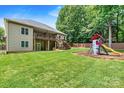 The lush backyard features a playset, a covered deck, and a lower patio perfect for entertaining at 1616 Indian Springs Nw Dr, Conover, NC 28613