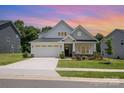Charming single-Gathering home featuring a two-car garage, manicured lawn, and welcoming front porch at sunset at 218 Tetcott St, Mooresville, NC 28115