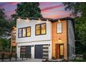 Charming duplex exterior showing modern design with wood, white brick, black trim, and stylish garage doors at 4117 Sarah Dr, Charlotte, NC 28217