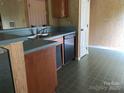 A kitchen features a stainless steel double sink, a dishwasher, wood cabinets, and green tile flooring at 5727 Dockside Dr, Charlotte, NC 28227