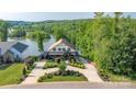 Beautiful exterior view of tan home with manicured landscaping, circular driveway and lake in the background at 5888 Wood Duck Way, Catawba, NC 28609