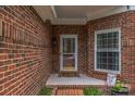 Close up of the front door area surrounded by brickwork with a window to the right at 9137 Brightleaf Pl, Charlotte, NC 28269