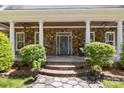 Inviting front porch with stone accents, decorative plants, ceiling fans, and a stylish front door with sidelights at 9261 Marvin School Rd, Marvin, NC 28173