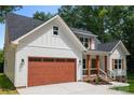 Beautiful craftsman-style home with white siding, dark roof, and a warm, inviting front porch with natural wood accents at 1004 E Sandy Ridge Rd, Monroe, NC 28112