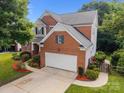 Aerial view of a brick home featuring a two-car garage, well-manicured lawn, and mature trees at 10919 Valley Spring Dr, Charlotte, NC 28277