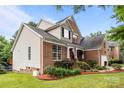 Exterior of a brick home with lush lawn, decorated front porch, and an attached two-car garage at 10919 Valley Spring Dr, Charlotte, NC 28277