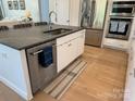 Modern kitchen island features a granite countertop, a stainless steel dishwasher, and hardwood floors at 11404 James Coy Rd, Davidson, NC 28036