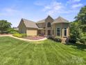 Stunning home featuring a well-manicured lawn, beautiful landscaping, and unique architectural details at 122 Long Cove Ln, Mooresville, NC 28117