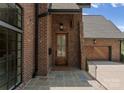 Elegant front entrance with stone tile, a wooden door, and a brick facade, complemented by stylish lighting at 2921 Windsor Ave, Charlotte, NC 28209