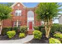 Charming front entrance with red door, brick facade, manicured shrubs and a sidewalk at 3213 Strawberry Rd, Matthews, NC 28104