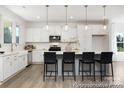 Bright kitchen with white cabinets, a central island with seating, and modern globe pendant lighting at 36140 Greg Norman Dr # 1003, Lancaster, SC 29720