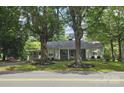 Traditional home with a welcoming front porch, complemented by mature trees and landscaping at 415 S Central Ave, Locust, NC 28097