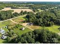 Aerial view of new construction farmhouse on acreage surrounded by mature trees and rolling fields at 5015 Lancaster Hwy, Monroe, NC 28112