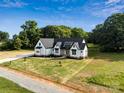 Stunning modern farmhouse with lush green lawn and wooded backdrop on a bright, sunny day at 5015 Lancaster Hwy, Monroe, NC 28112