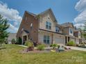 Exterior shot showcasing the landscaped lawn and brick and stone facade of this charming home at 5020 Forest Hills Pl, Fort Mill, SC 29707